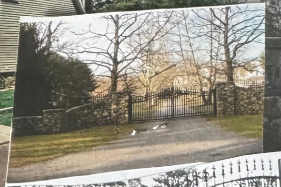 Black iron estate entrance gate installed between stone walls