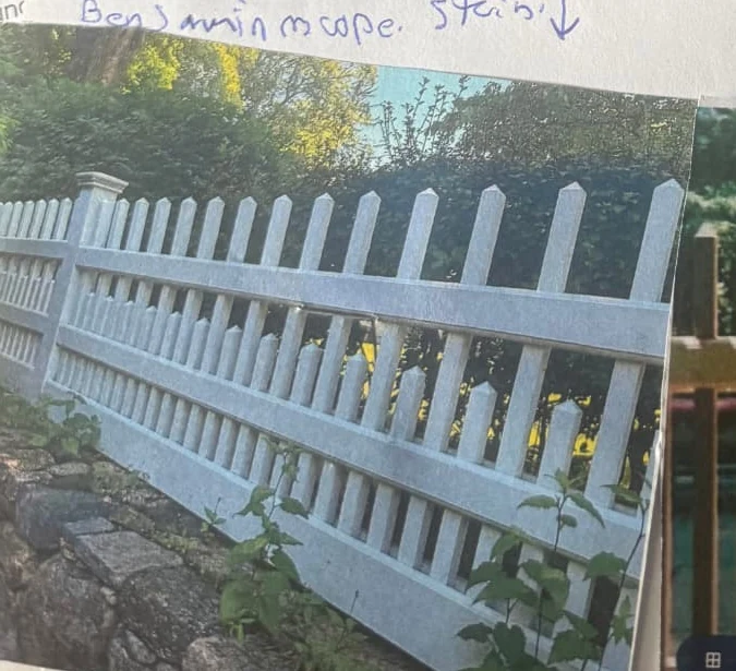 White picket fence installed along a stone garden wall