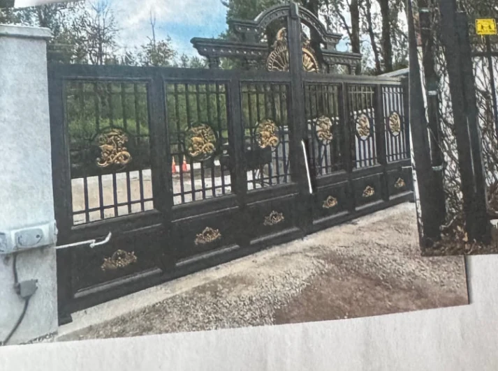 Black automated driveway gate with gold ornamental details