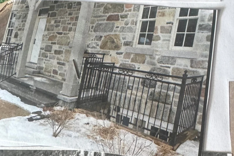 Custom black iron railing installed along a stone residence