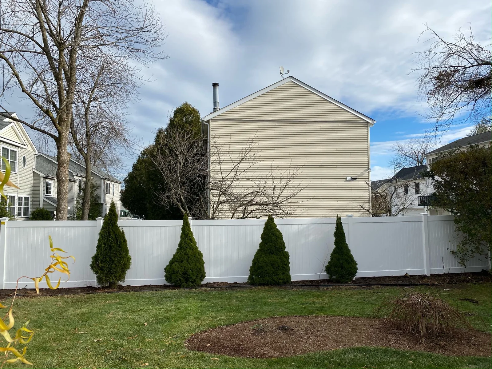 White vinyl privacy fence in a landscaped backyard