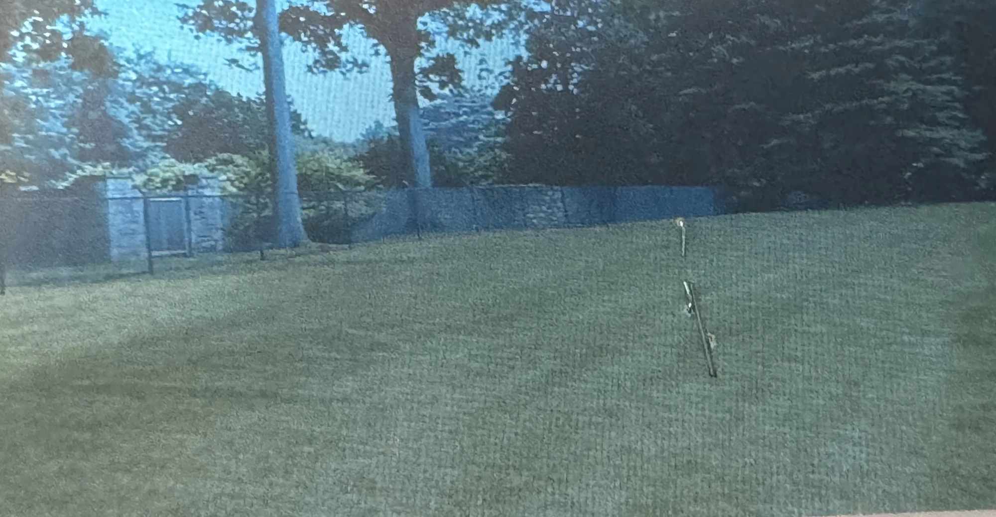 Privacy perimeter fence across a large green lawn