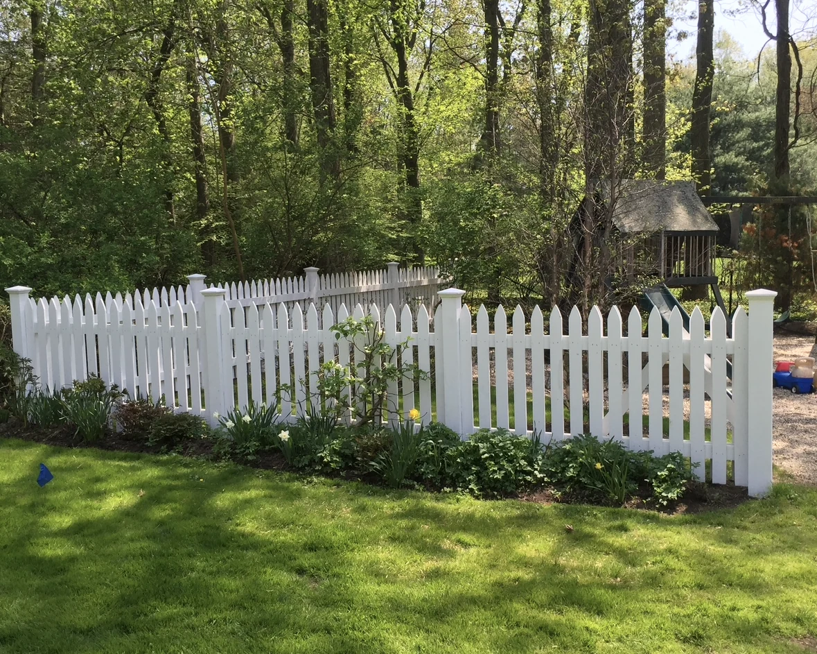 White picket fence enclosing a wooded backyard