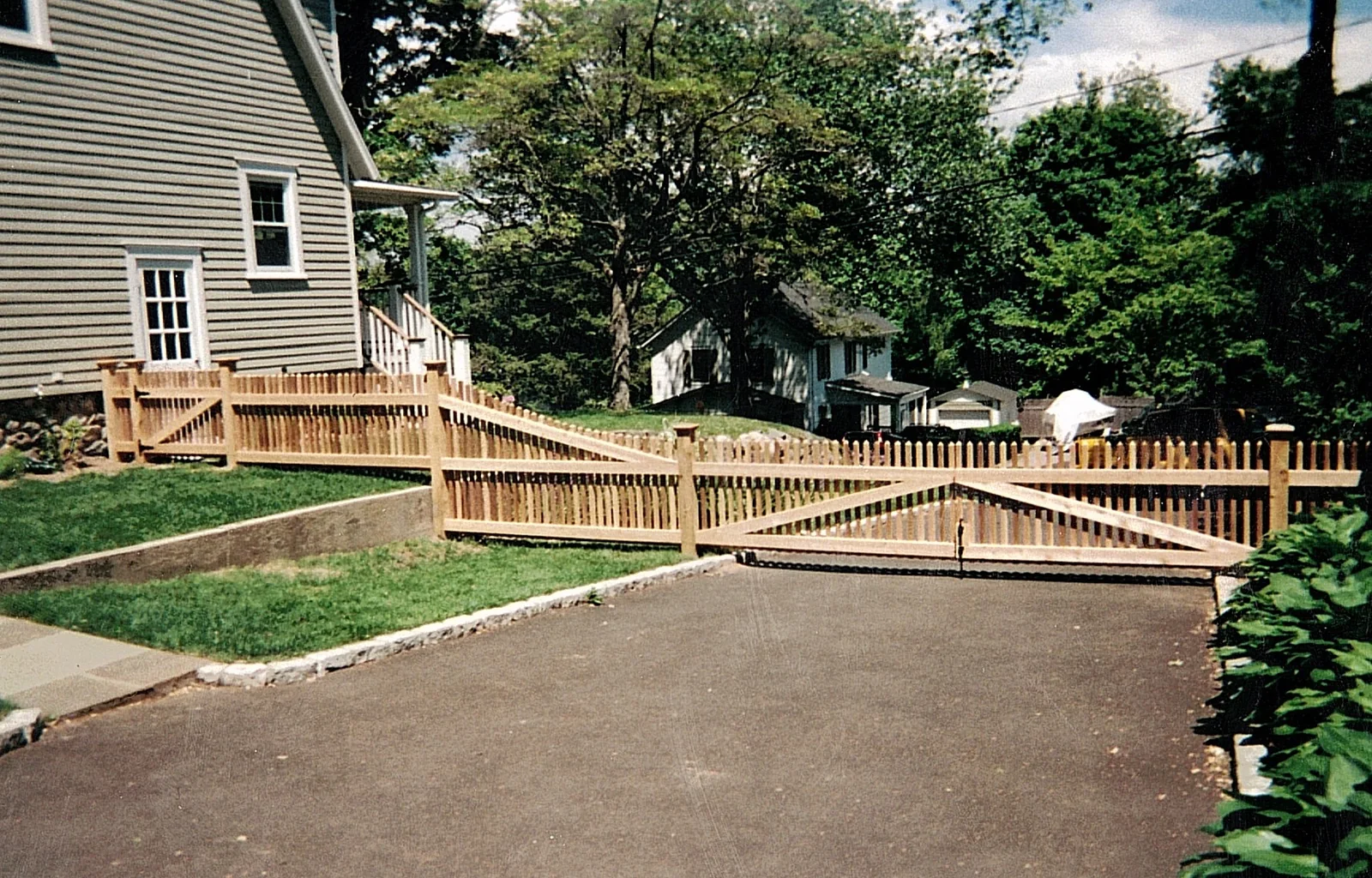 Cedar driveway gate and picket fence across a residential driveway