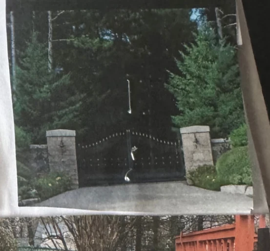 Curved black automated estate gate between stone pillars