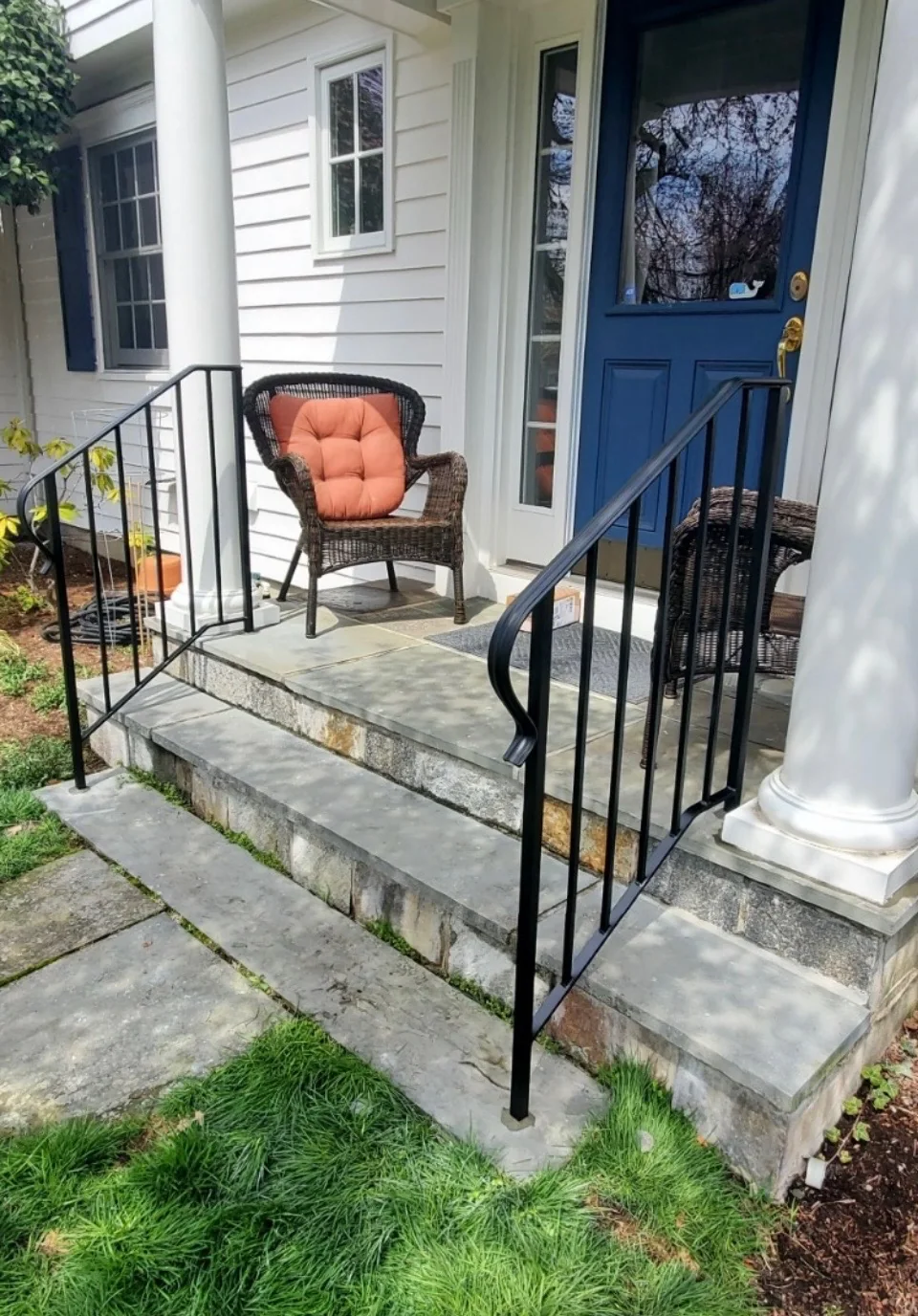 Custom black iron railings installed on stone front steps